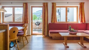 A room with a dining area, a sofa, and a view of the outdoors. - Luxury apartment with wellness next to gondola (Brixen im Thale)