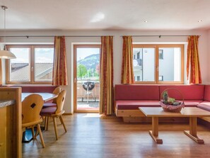 A room with a dining area, a sofa, and a view of the outdoors. - Luxury apartment with wellness next to gondola (Brixen im Thale)