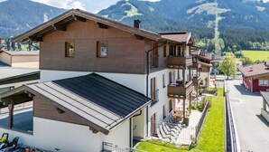 A multi-story building with a sloped roof, balconies, and a view of mountains. - Luxury apartment with wellness next to gondola (Brixen im Thale)