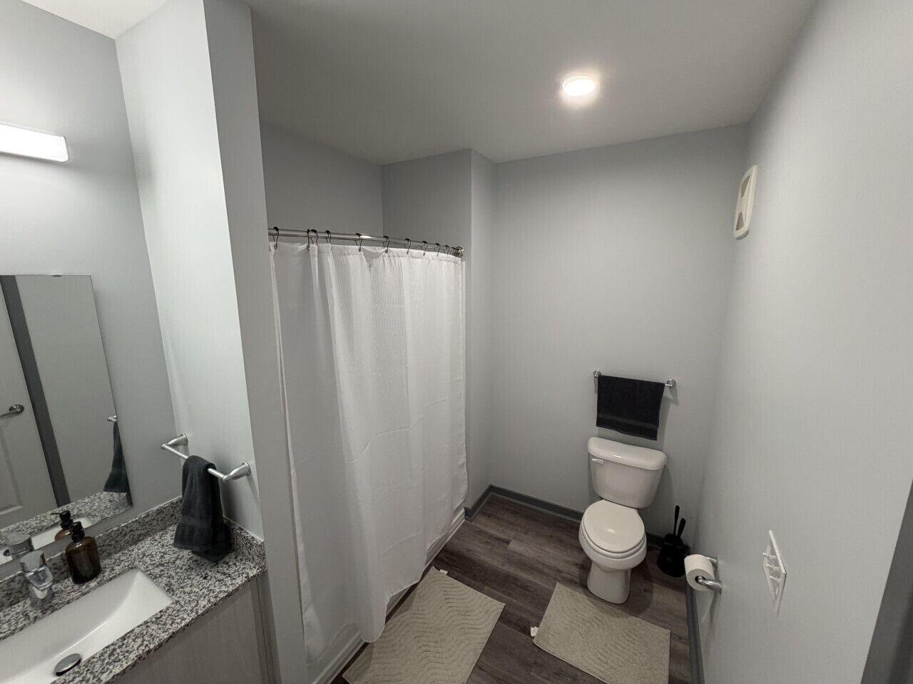 Un bagno con tenda della doccia, WC, lavandino e specchio.