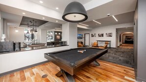 A modern indoor pool area with a pool table, seating, and a bar area. - Fast Lane Flat: Walk to Track, Dining & Parking (Speedway)
