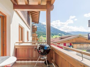 A balcony with a barbecue grill, wooden railings, and a view of mountains. - Luxury apartment with spa next to the gondola (Brixen im Thale)