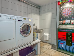 Ein Waschraum mit zwei Waschmaschinen, einem Waschbecken und einem Dartspiel.