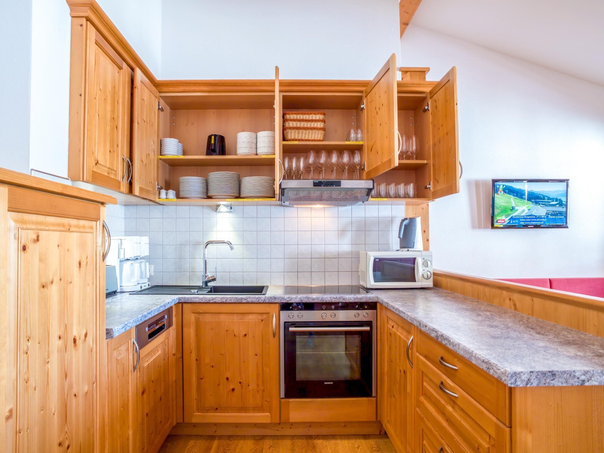 A compact kitchen with wooden cabinets, a built-in microwave, a dishwasher, and a stove.