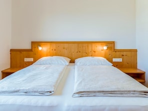 Ein Doppelbett mit Holz-Kopfteil, zwei Nachttische und Wandleuchten zum Lesen.