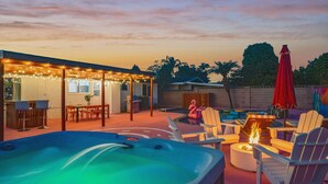 Un bain à remous, un espace extérieur aménagé avec des sièges et une terrasse couverte décorée de guirlandes lumineuses.