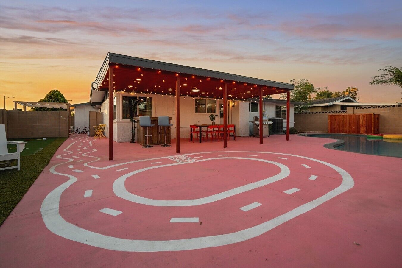 A covered patio area with a pool, outdoor seating, and a winding path.