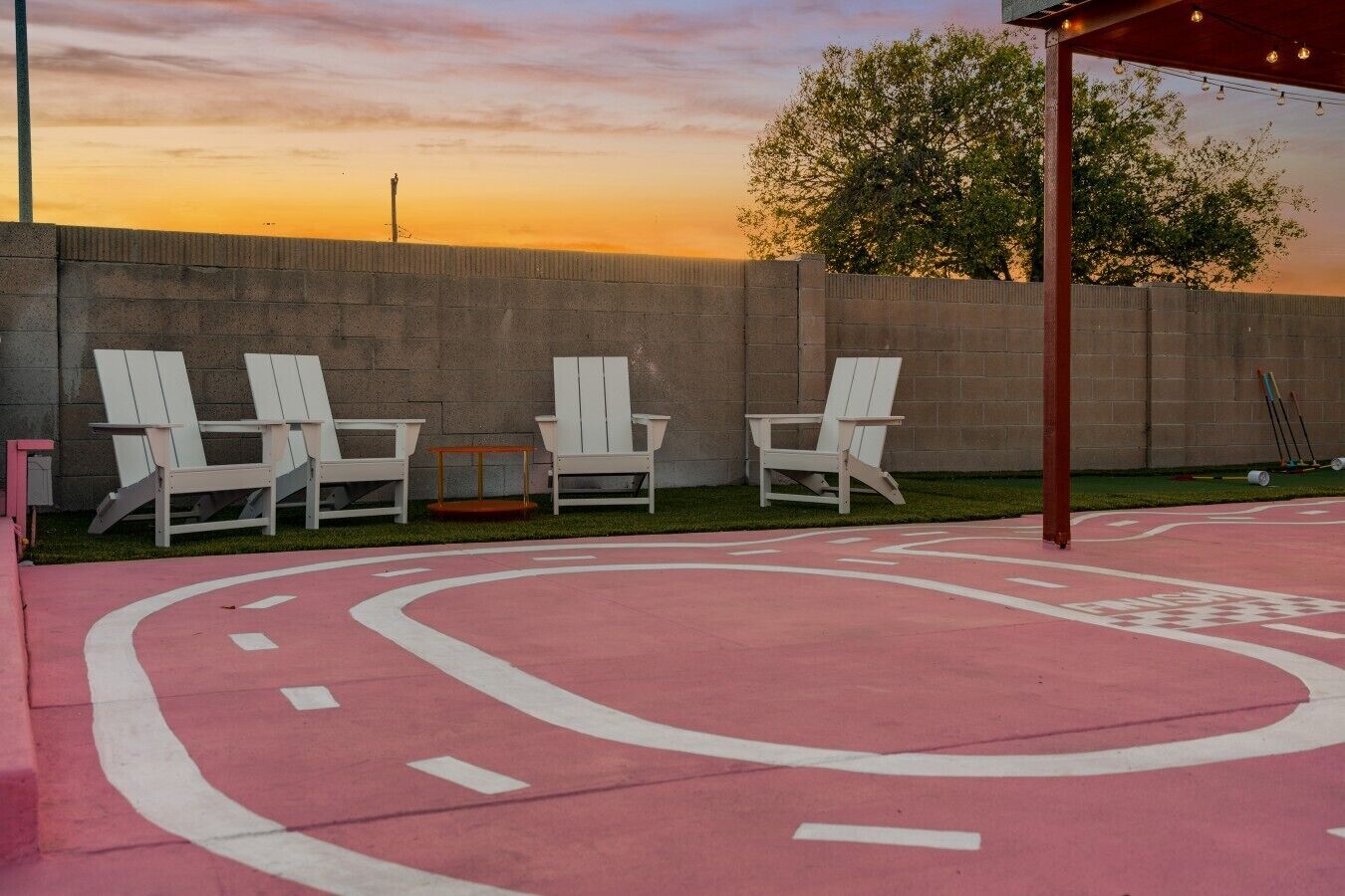 A patio area with Adirondack chairs, a small table, and a concrete wall.