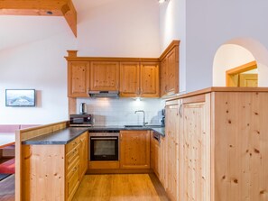 Une cuisine avec des meubles de rangement en bois, un four à micro-ondes, un four traditionnel et un évier.
