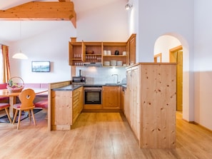 A compact kitchen with wooden cabinets, a microwave, and a sink. - Deluxe apartment with spa next to the gondola (Brixen im Thale)