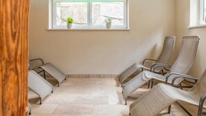 A waiting area with chairs, a window with plants, and a tiled floor. - Deluxe apartment with spa next to the gondola (Brixen im Thale)