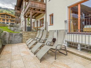 Une terrasse avec des fauteuils de jardin, un mur en pierre et une vue sur une montagne.