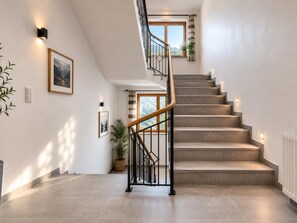 A modern staircase with a wooden handrail, a view of the outdoors through a window, and a framed picture on the wall. - Modern apartment for 16 people near the gondolas (Kirchberg in Tirol)