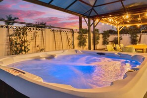 Ein Whirlpool unter einem überdachten Bereich mit Blick auf einen Sonnenuntergang.