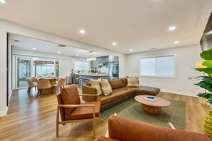 Ein geräumiges Wohnzimmer mit einer großen Couch, einem Couchtisch und einem Essbereich mit Stühlen.