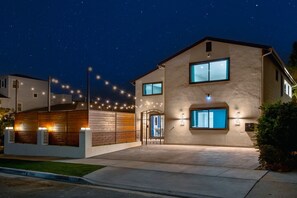 Ein zweistöckiges Haus mit einem großen Eingangsbereich, einer Garage und gut beleuchteter Fassade.