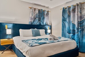 Ein modernes Schlafzimmer mit einem großen Bett, Nachttischlampen und Vorhängen.