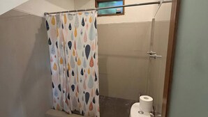 Un bagno con il water, una doccia, una tenda da doccia decorata e una piccola finestra.