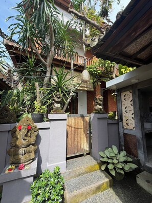 A courtyard with a traditional gate, potted plants, and a statue. - Room-a Quiet Room With Balcony in Nyuh K (Ubud)