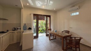 Una cucina compatta con zona pranzo, una porta scorrevole in vetro che dà su un giardino e una ventola a soffitto.