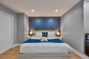Ein Schlafzimmer mit einem Bett, Nachttischlampen, einem Kopfteil und einem Holzboden.