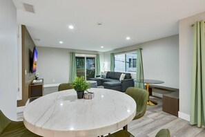 Ein modernes Wohnzimmer mit einem runden Marmortisch, einem grauen Sofa und einem an der Wand befestigten Fernseher.