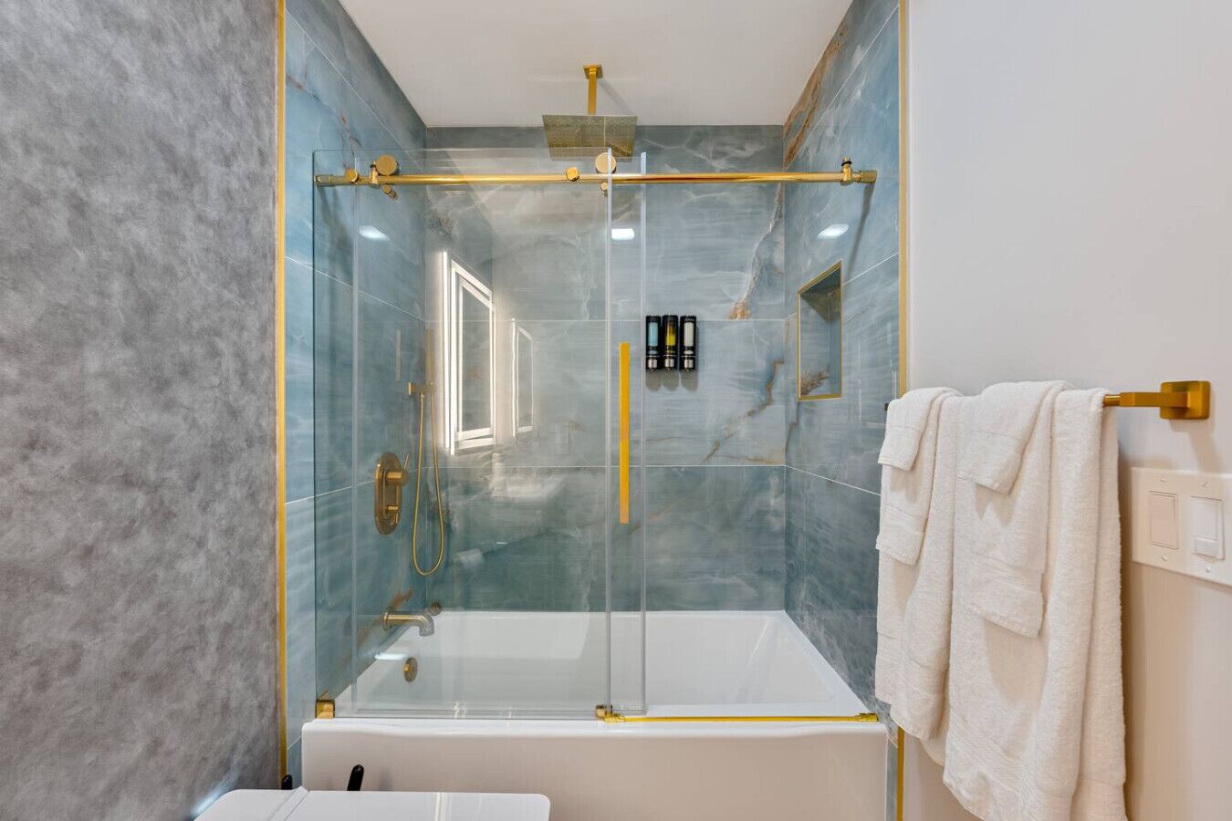Een moderne badkamer met een douchecabine van glas, een wit bad en een handdoekrek.