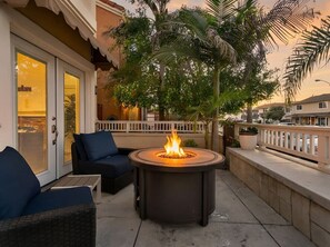 A patio with outdoor furniture, a fire pit, and a view of a residential area.