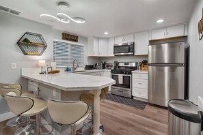 A modern kitchen with a central island, stainless steel appliances, and a hexagonal wall shelf. - Steps to Lake Tahoe | Fenced Yard | Modern Cabin (South Lake Tahoe)