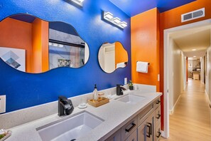 Ein modernes Badezimmer mit zwei Waschbecken, einem großen Spiegel und einer Duschkabine.