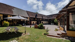 Ein Innenhof mit Tisch und Stühlen, einem überdachten Sitzbereich und einem Gebäude im traditionellen Baustil.