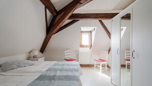 Ein Schlafzimmer mit einem Bett, zwei Stühlen, einem Nachttisch, einem Fenster und einem Kleiderschrank.