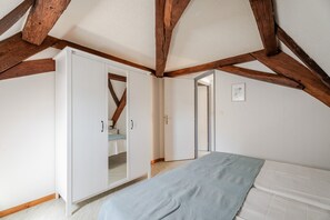 A bedroom with a bed, wardrobe, and a door leading to another room. - Grand Gîte Le Bleuet "bi's anstetts" (Issenhausen)