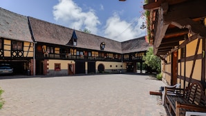 Ein Innenhof mit einem traditionellen Gebäude, das einen Balkon, eine Uhr und einen kleinen Turm zeigt.