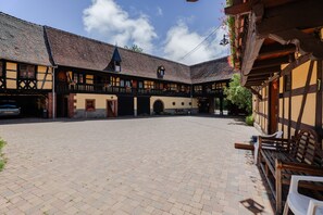 Une cour intérieure avec un bâtiment traditionnel doté d’un balcon, d’une horloge et d’une petite tour.