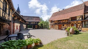 Ein Innenhof mit traditionellen Fachwerkhäusern, einem gepflasterten Bereich und Blumentöpfen.