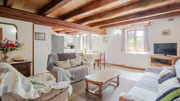 Un salon chaleureux avec un plafond en bois, un canapé, une table à manger et un téléviseur.