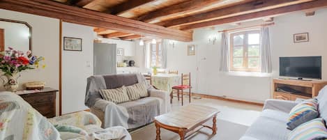 Un salon chaleureux avec un plafond en bois, un canapé, une table à manger et un téléviseur.