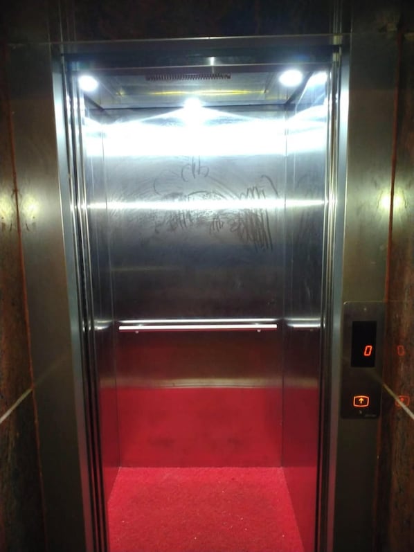 An elevator with metallic walls, a red carpet, and a digital display showing the number 0. - International HotelBaikuntha nr.sea Puri (Puri)