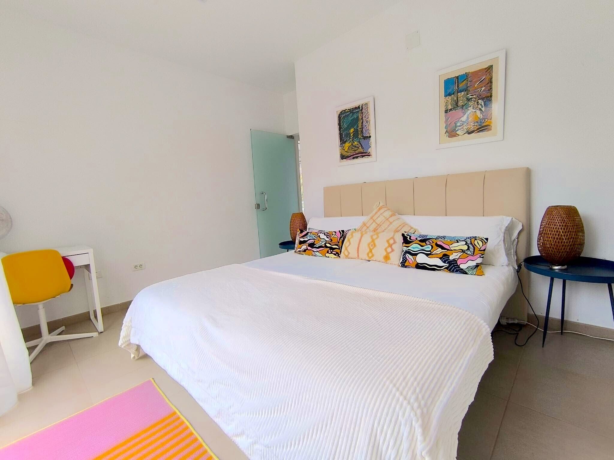Un dormitorio con una cama, un escritorio, una silla y dos cuadros en la pared.