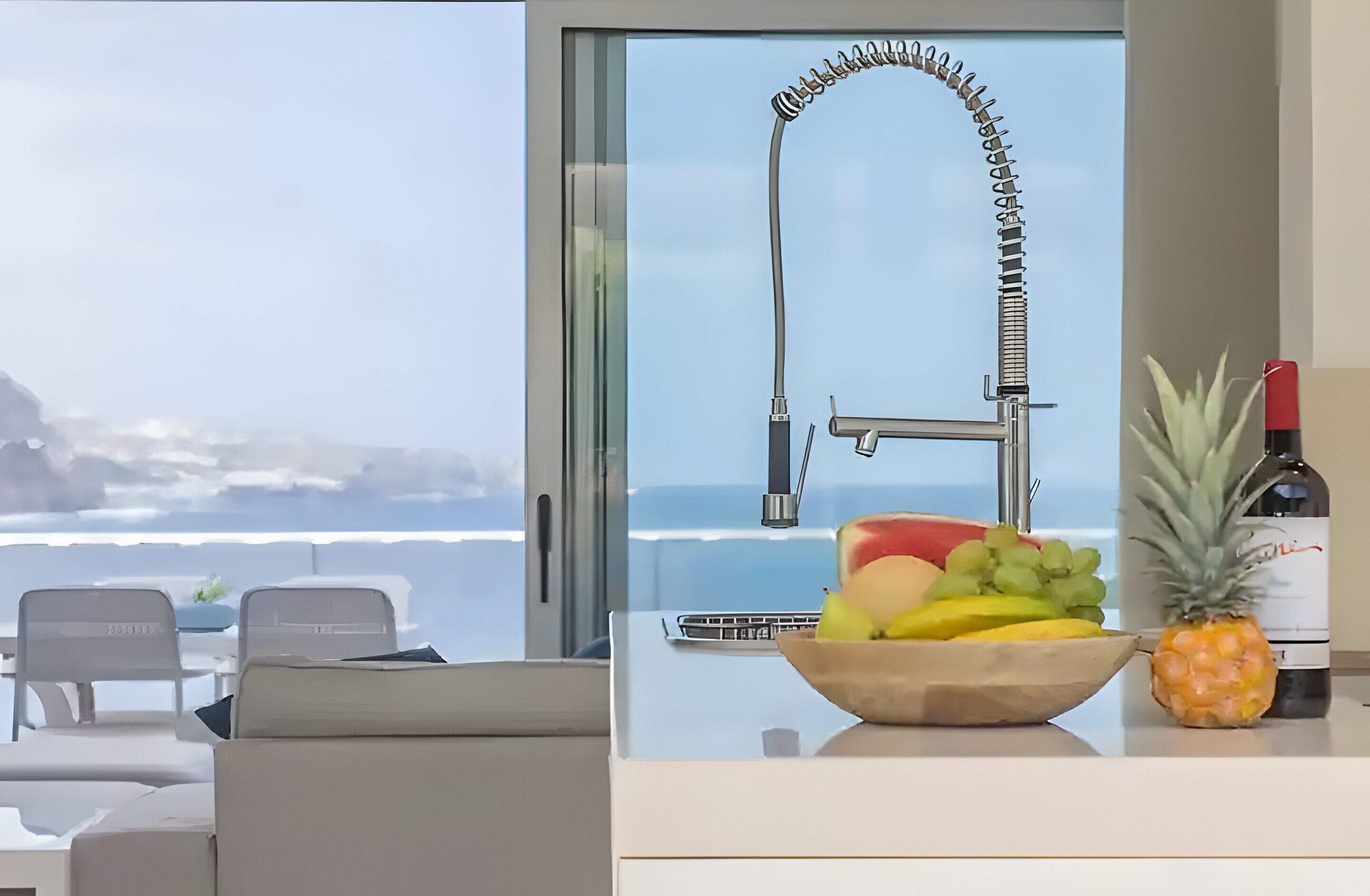 Eine moderne Küche mit Meerblick, eine Fruchtschale auf der Arbeitsplatte und eine Weinflasche.