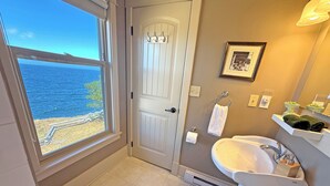 Une salle de bain avec vue sur la mer, une porte blanche, un lavabo et des toilettes.