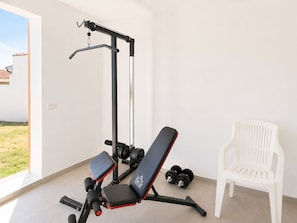 Ein Heimfitnessraum mit einer Langhantelbank, Kurzhanteln und einer Klimmzugstange.