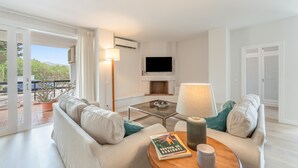 Ein modernes Wohnzimmer mit einer Couch, einem Couchtisch, einer Lampe, einem Flachbildfernseher und einem Kamin.