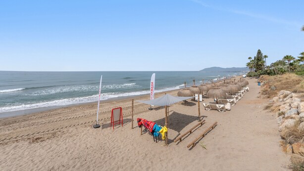 Ein Strand mit Sonnenschirmen, Liegestühlen und einer Flagge.
