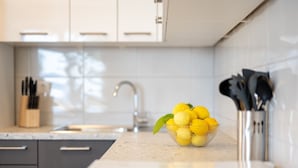 A kitchen with a bowl of lemons on the counter, a knife block, and a modern faucet.
