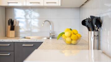 A kitchen with a bowl of lemons on the counter, a knife block, and a modern faucet.