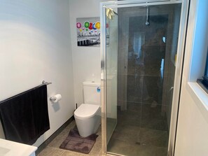 Ein Badezimmer mit Toilette, Dusche und Handtuchhalter.