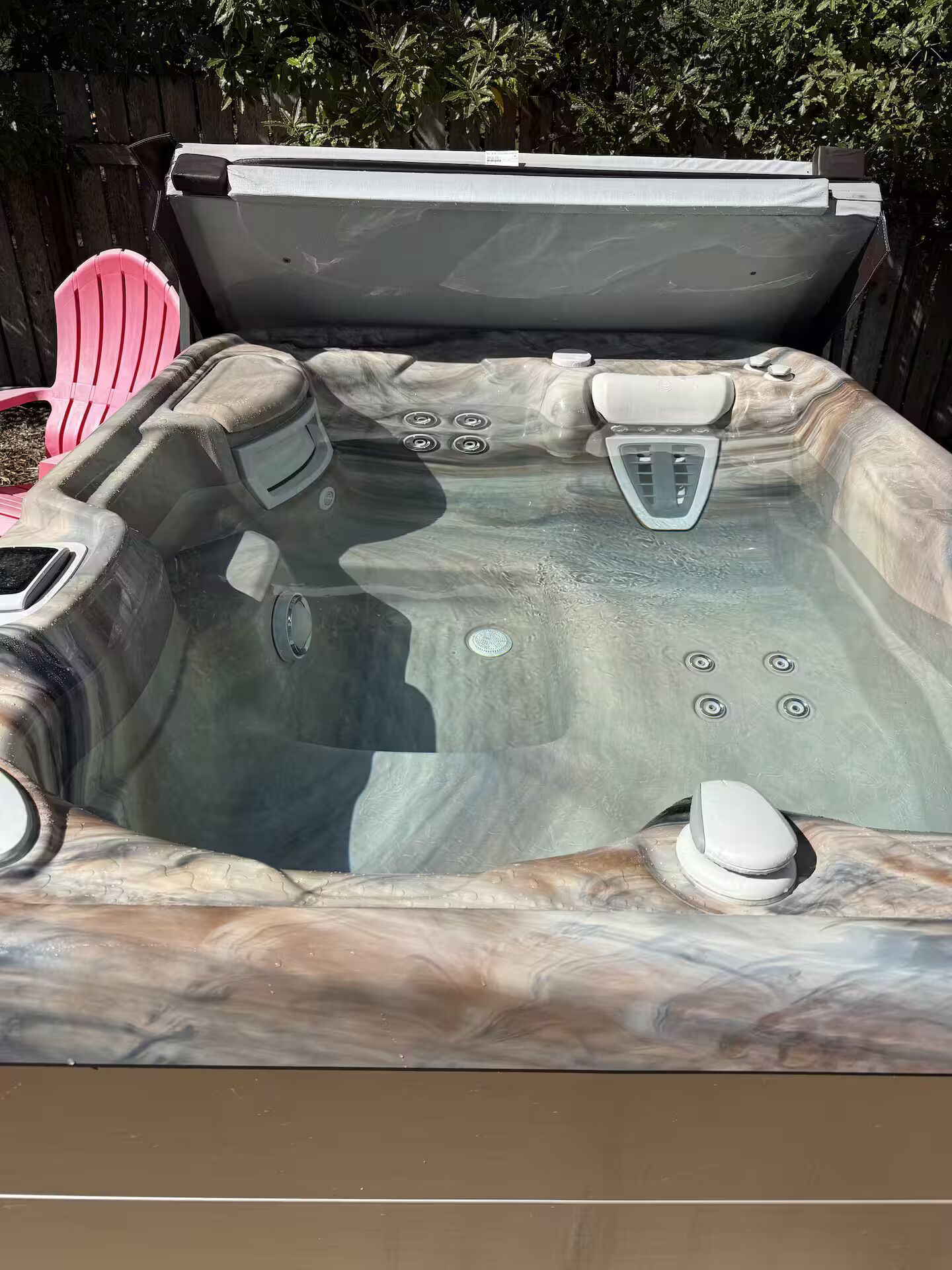A hot tub with a marble-like exterior, a cover, and a drain.