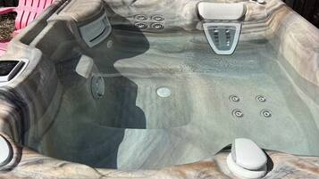 A hot tub with a marble-like exterior, a cover, and a drain.